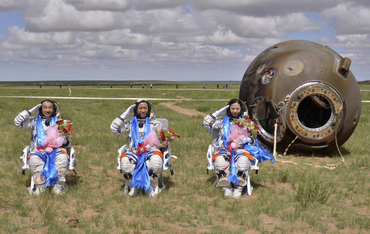 Image: Astronauts salute after returning to earth in re-entry capsule of China's Shenzhou-10 spacecraft at its main landing site in north China's Inner Mongolia Autonomous Region