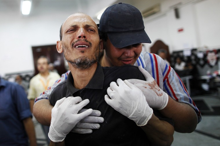 Image: A man grieves at a makeshift hospital where victims are being brought following clashes between Egyptian police and Muslim Brotherhood supporters.
