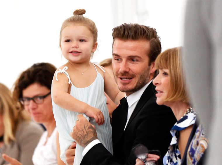 Image: Former England soccer captain David Beckham holds his daughter Harper as he speaks to Vogue editor Anna Wintour while waiting for a presentation of the Victoria Beckham Spring/Summer 2014 collection during New York Fashion Week