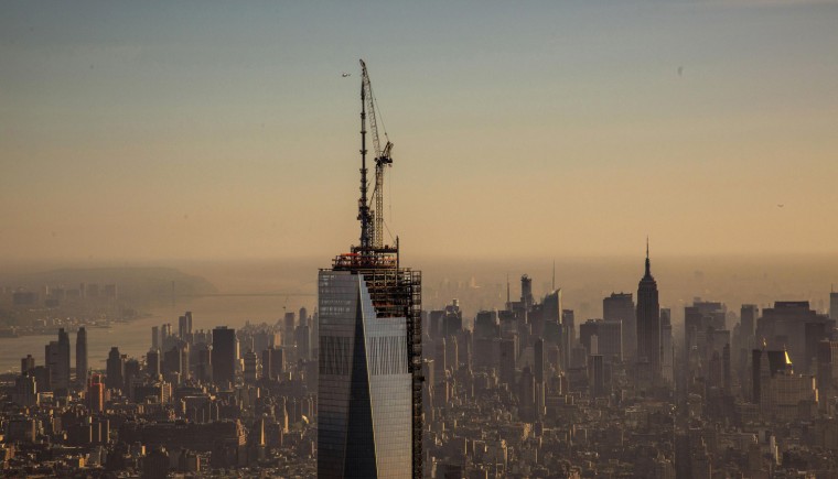Image: The final piece of the One World Trade Center spire is attached to the building by ironworkers in New York