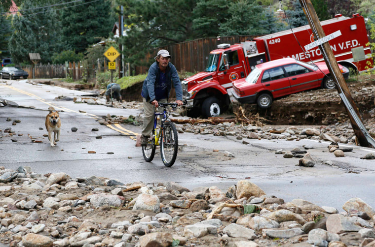 Image: A resident rides down Main Street with his dog in Jamestown, Colorado, after a flash flood destroyed much of the town