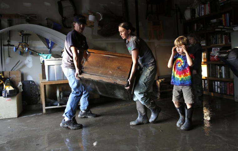 Image: Chris and Shanda Roberson carry a flood soaked antique trunk from their garage in Longmont