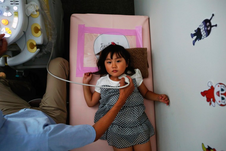 Image: A doctor conducts a thyroid examination on four year old Maria Sakamoto  brought by her mother to the office of Iwaki Radiation Citizen Centre NPO in Iwaki town