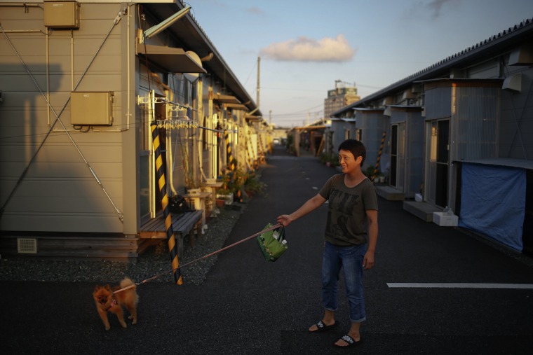Image: Kasumi Saino from the town of Tomioka near the tsunami-crippled Daiichi nuclear power plant walks her dog May between pre-fabricated houses of center for evacuees where she lives in Iwaki