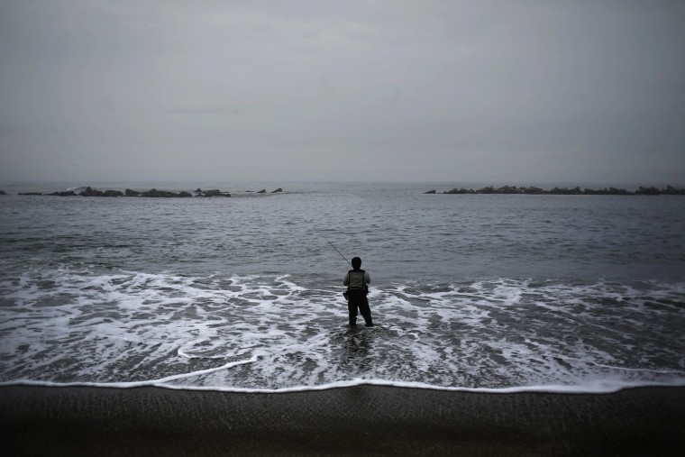 Image: A man fishes on a municipal beach that is closed for public near Iwaki town, south of the tsunami-crippled Fukushima Daiichi nuclear power plant in Fukushima prefecture