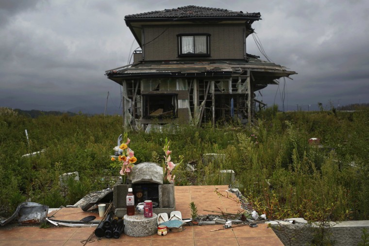 Image: A small monument to victims is seen in front of an abandoned house at the tsunami destroyed coastal area of the evacuated town of Namie