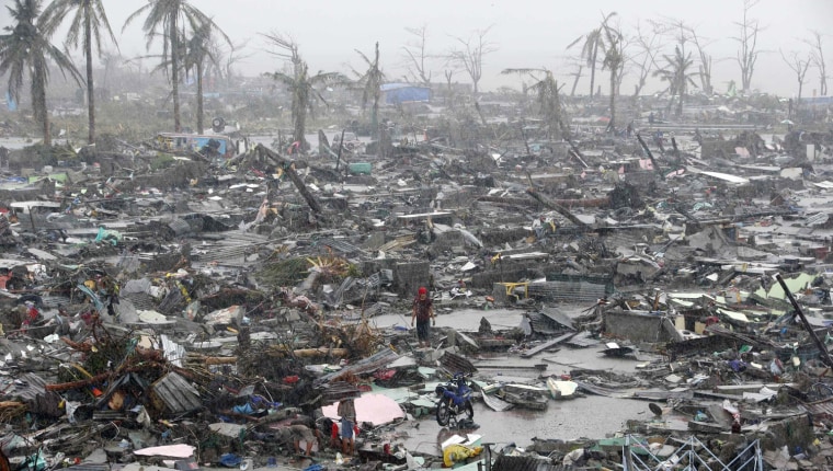 Image: Survivors stand among debris and ruins of houses destroyed after Super Typhoon Haiyan battered Tacloban city in central Philippines