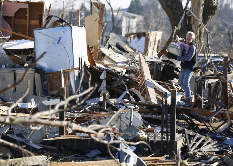Image: Boy picks through belongings in the destruction caused by a tornado that touched down in Washington