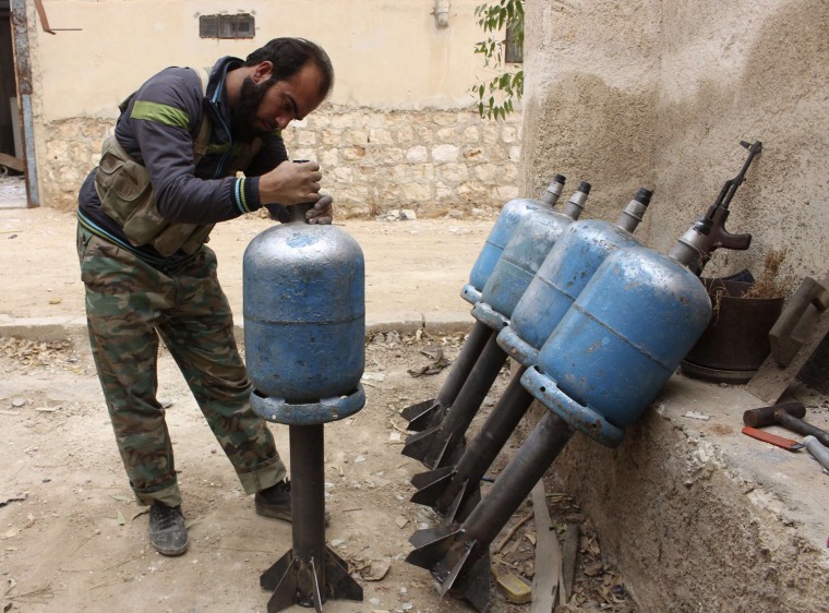 Image: A fighter from the Tawhid Brigade, which operates under the Free Syrian Army, prepares homemade rockets to be thrown towards the 80th Brigade base in Aleppo