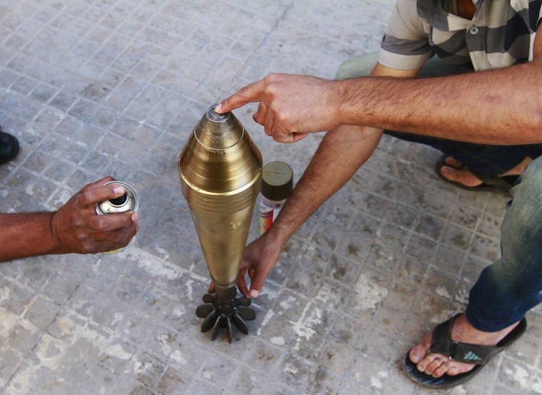 Image: Free Syrian Army fighters spray paint on an improvised mortar shell at a weapon factory in Aleppo