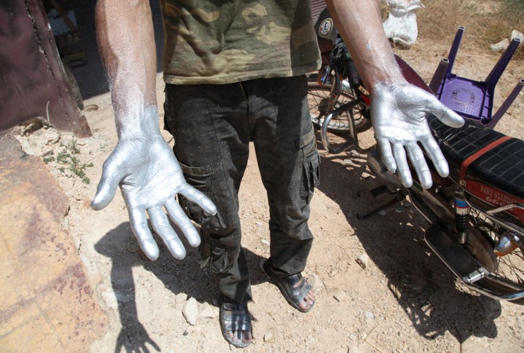 Image: A Syrian rebel with hands coated with an aluminum-based ingredient while preparing a homemade bomb.