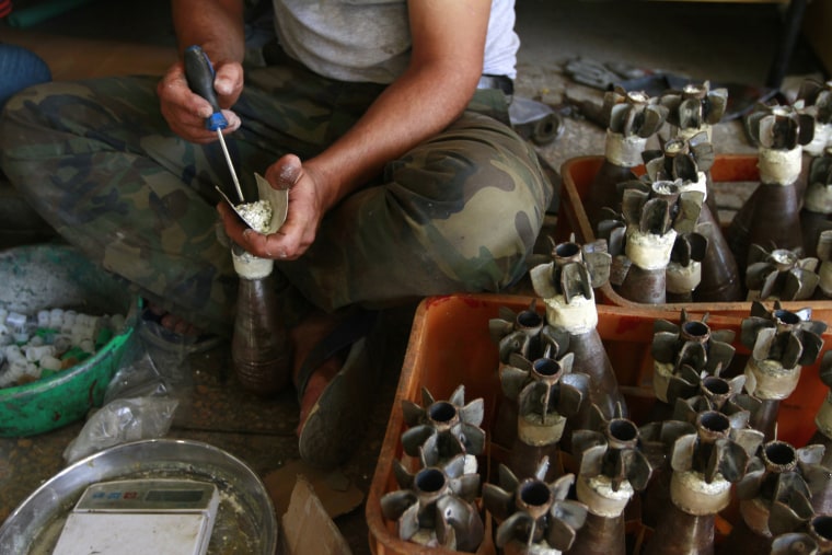 Image: A Free Syrian Army fighter makes improvised mortar shells at a weapons factory in Aleppo