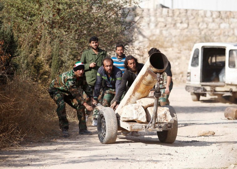 Image: Fighters from the Tawhid Brigade, which operates under the Free Syrian Army, drag a rocket launcher near the 80th Brigade base in Aleppo