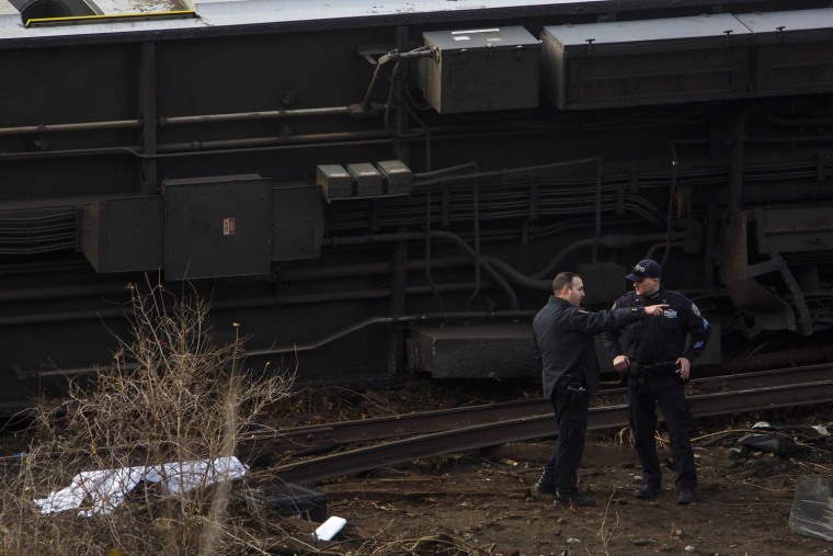 Image: Emergency workers stand near the the site of a Metro-North train derailment in the Bronx borough of New York