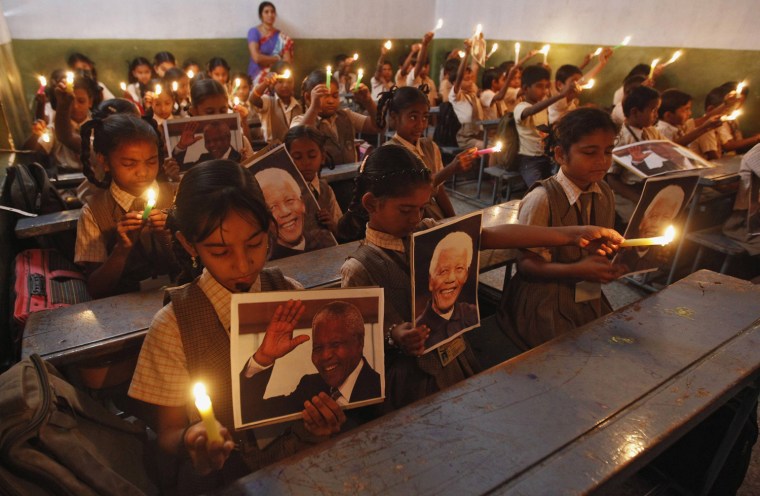 Image: Schoolchildren hold candles and portraits of former South African President Mandela during prayer ceremony at school in western Indian city of Ahmedabad