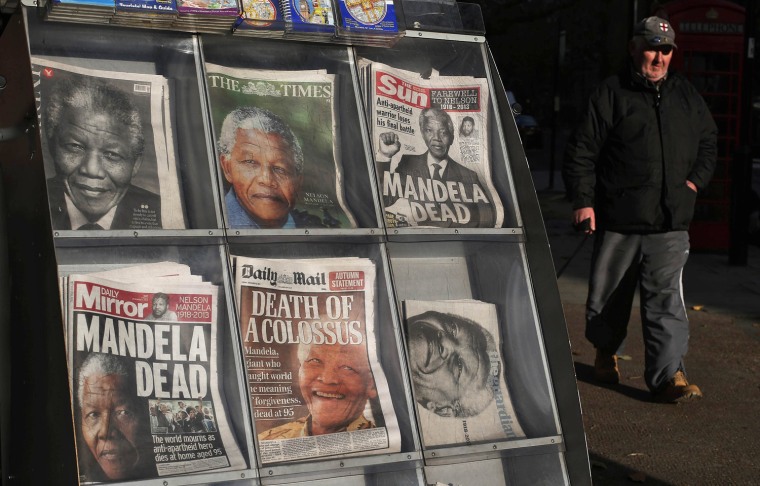 Image: A man walks past a case containing British newspapers with headlines about the death of South Africa's former president Nelson Mandela outside of a news agent in London