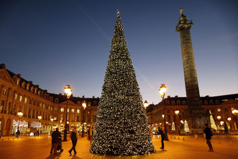 Image: People walk near a Christmas tree in front of the Vendome Column as part of Christmas holiday  season illuminations at Place Vendome in Paris
