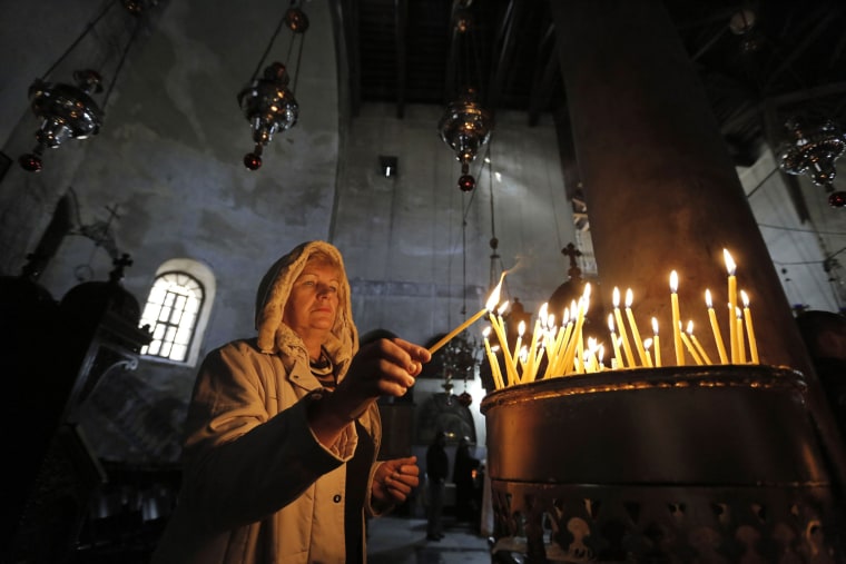 Image: A tourist lights a candle at the Church of Nativity, revered as the site of Jesus' birth, ahead of Christmas in the West Bank town of Bethlehem