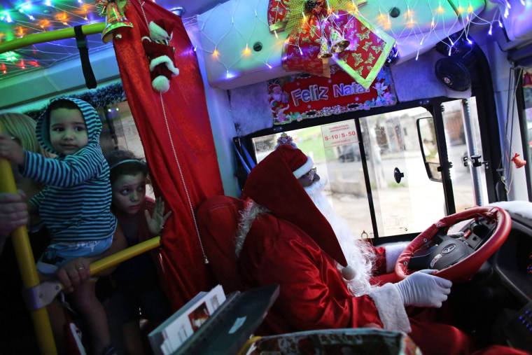 Image: Bus driver Edilson, also known as \"Fumassa\", drives while wearing a Santa Claus outfit inside an urban bus decorated with Christmas motives in Santo Andre