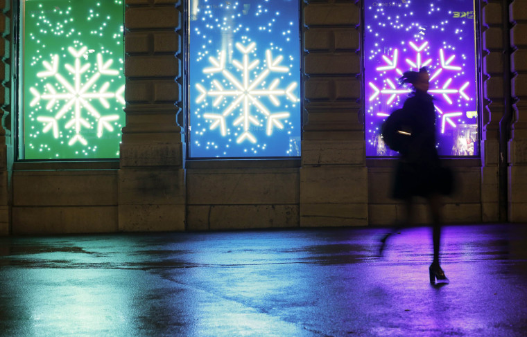 Image: A woman runs past Christmas illuminations at the Paradeplatz square in Zurich