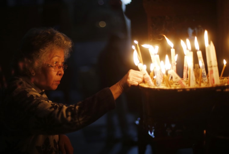 Image: A woman holds a burning candle during a visit to the Church of Nativity in Bethlehem on Christmas day