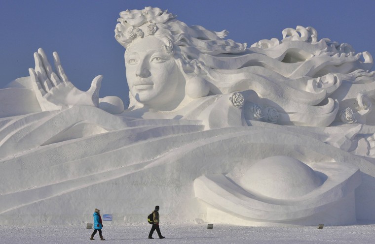Image: Visitors walk past a giant snow sculpture ahead of the 30th Harbin Ice and Snow Festival in Harbin