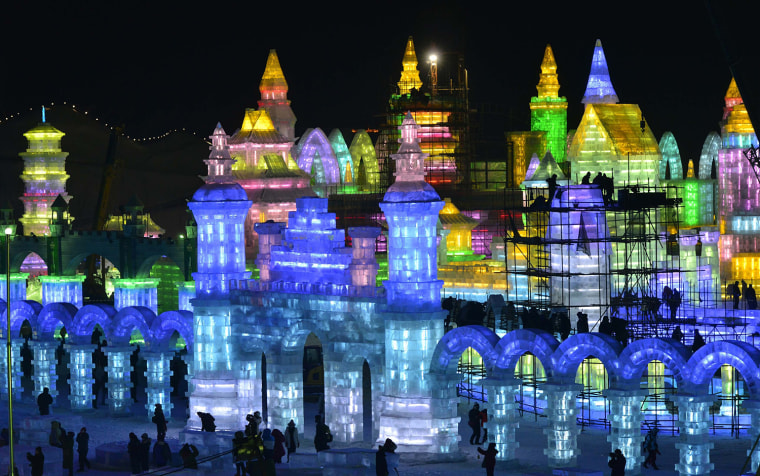 Image: Workers and scaffoldings are seen next to newly-built ice sculptures illuminated by coloured lights ahead of the 30th Harbin Ice and Snow Festival, in Harbin