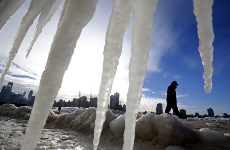 Image: Man is framed by icicles as he walks along a beach in Chicago