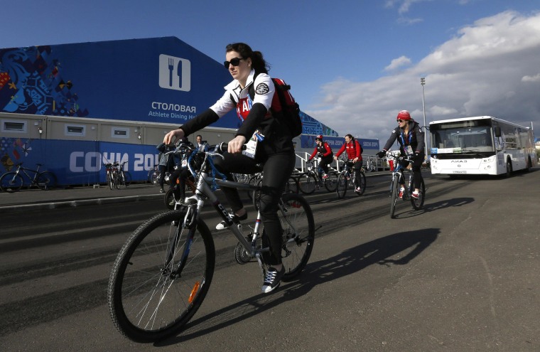 Image: Members of Canada's Olympic team ride bicycles in the Coastal Athlete's Village at the Olympic Park in Sochi