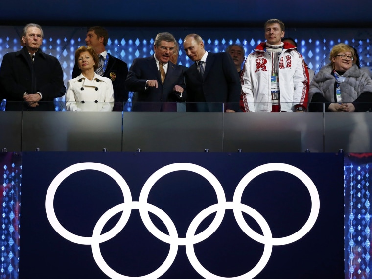 Image: International Olympic Committee President Thomas Bach speaks with Russian President Vladimir Putin as gold medallist in the four-man bobsleigh Alexander Zubko (2nd R) looks on in the closing ceremony for the Sochi 2014 Winter Olympic Games