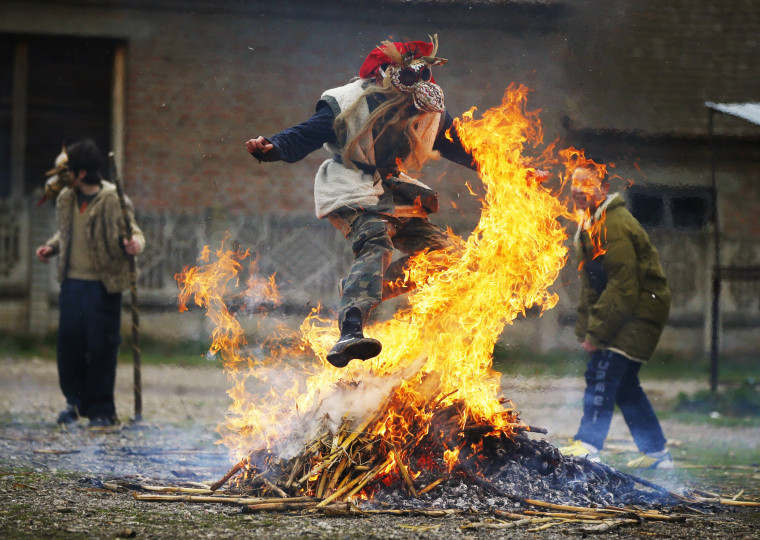 Image: Boy wearing a mask jumps over a fire during Bele Poklade carnival celebrations in the village of Lozovik