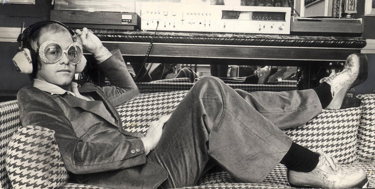 Elton John sitting on a settee with headphones on, September 1974. (Express Newspapers Via AP Images)