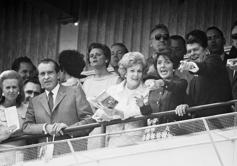 Like typical race fans, Gov. Ronald Reagan and his wife Nancy excitedly follow the progress of a horse running in the sixth race of the Kentucky Derby program in Louisville, Ky., on May 3, 1969. President Richard Nixon and wife, Pat, are alongside the Reagans in first row of box. (AP Photo)