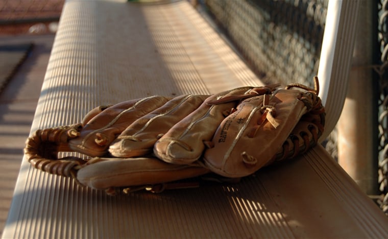 The soft glow of sunset falls on a baseball glove left on the bench after the game.