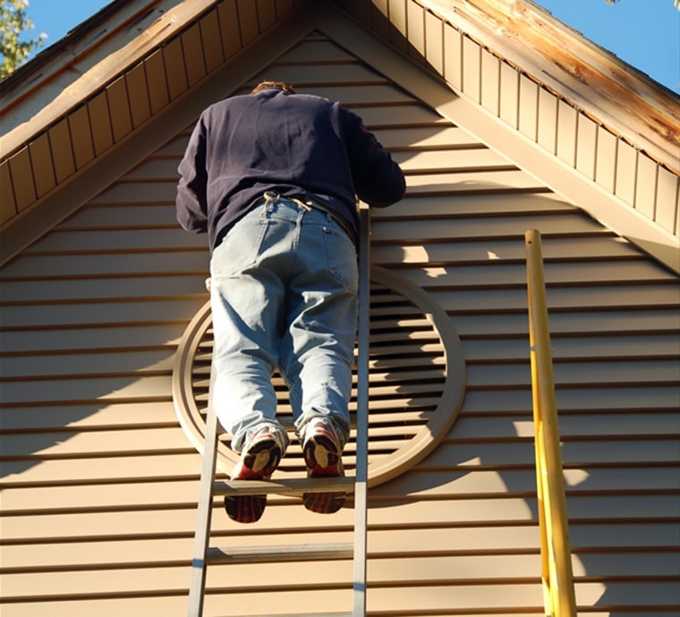 man on ladder repairing vinyl siding