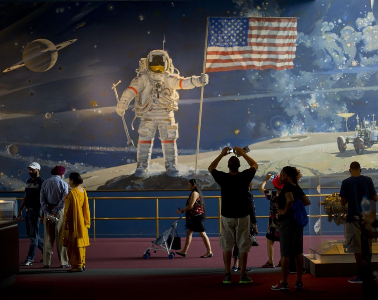 Visitors to the Smithsonian's National Air and Space Museum walk past a depiction of space exploration by artist Robert T. McCall titled \"The Space Mural: A Cosmic View,\" on July 20, the 45th anniversary of Apollo 11 lunar landing.