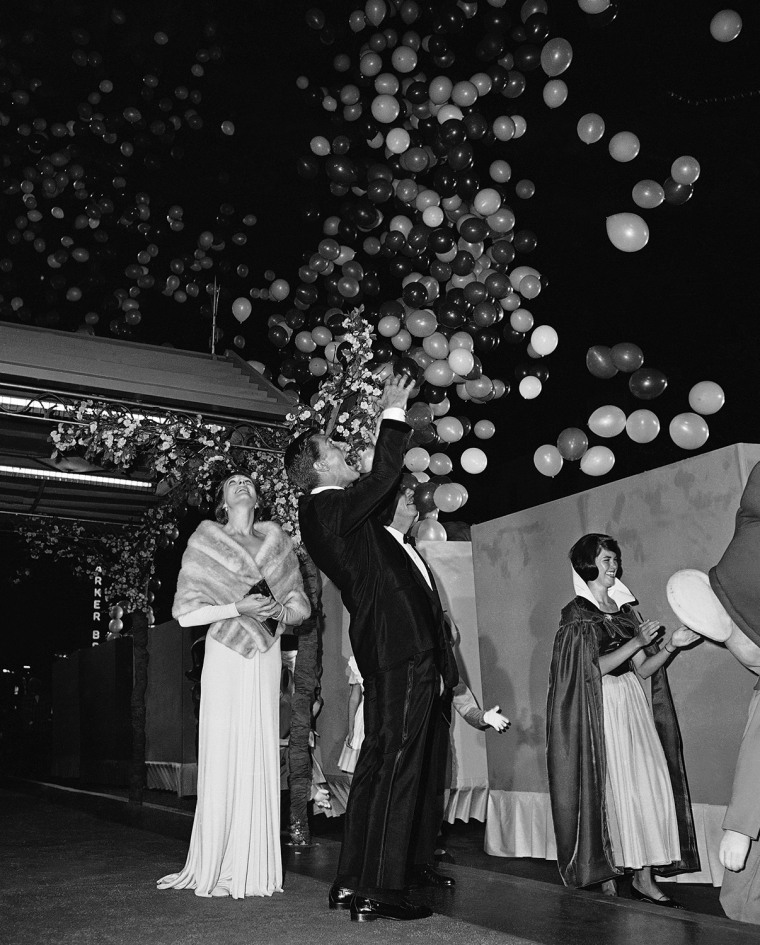 Co-stars Julie Andrews, left, and Dick Van Dyke, center, watch balloons fill the sky outside the theater just before the start of the world premier of Walt Disneys new movie, Mary Poppins, Aug. 28, 1964, Hollywood, Calif.  Walt Disney is in the background, almost hidden by Van Dyke. The woman on the right is unidentified. (AP Photo/Ed Widdis)