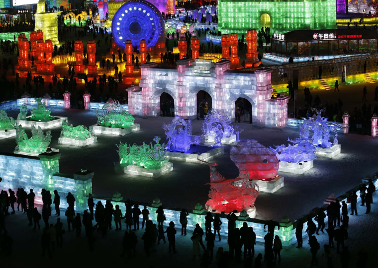 Image: People visit ice sculptures illuminated by coloured lights during the opening day of the 31st Harbin International Ice and Snow Festival in the northern city of Harbin