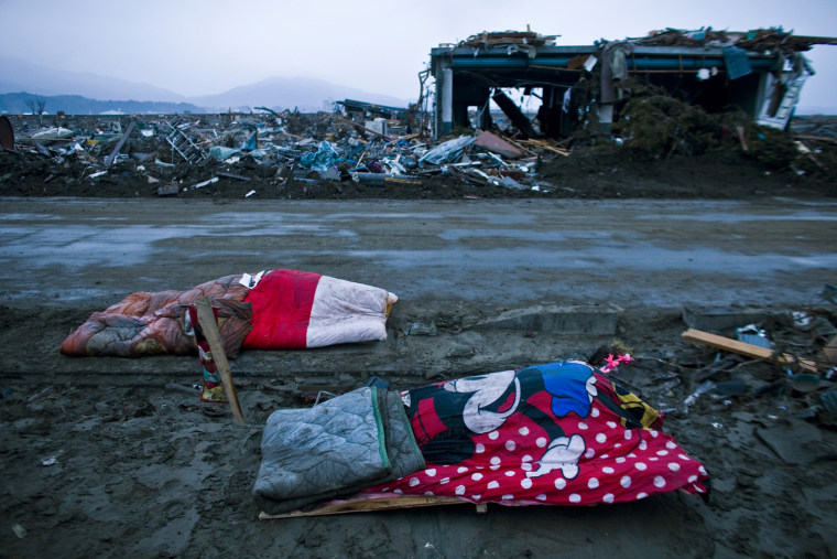 Image: Two bodies of victims from last week's earthquake and tsunami are left covered in blankets in the devastated town of Rikuzenmaeda in the Iwate prefecture of Japan.