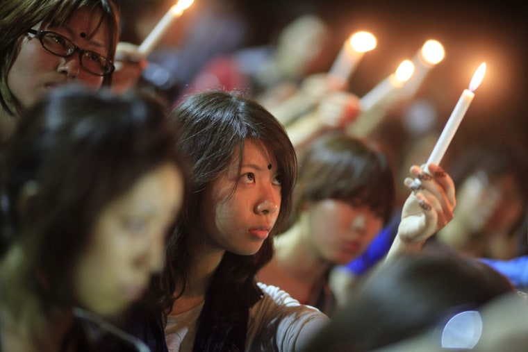 Image: A member of the volunteer organization, Green Belt Trust, holds a candle to pay tribute to the victims of Japan's earthquake and tsunami during a vigil at the campus of the University of Dhaka