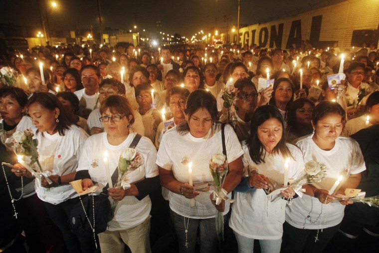 Image: PPeople hold candles as they pray for Japan's earthquake and tsunami victims during a ceremony at Japan Avenue in Lima