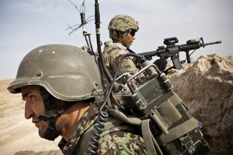 Image: A member of the Afghan National Army provides security with a soldier from the U.S. Army during a patrol near Command Outpost AJK in Maiwand District, Kandahar Province