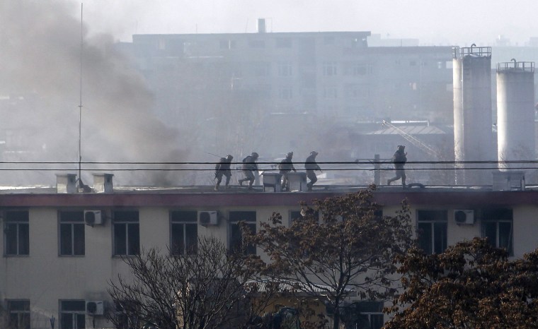 Image: Afghan security forces run on the roof of the Kabul traffic police headquarters as it is attacked by insurgents in Kabul