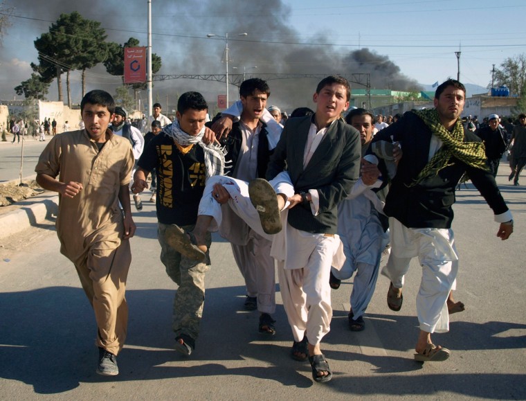 Image: Afghans carry a wounded man following attack on UN office