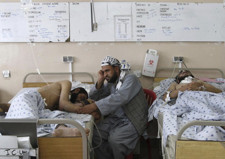 Image: An Afghan man attends to his wounded brother at a hospital after a roadside bomb blast in Panjwai district of Kandahar
