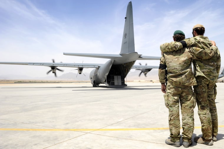 Image: Special forces soldiers embrace as the C-130 carrying Sergeant Brett Wood departs Tarin Kot Airfield in Uruzgan