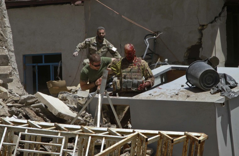 Image: A wounded Italian soldier is being helped after a blast near a foreign base in Herat