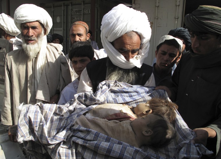 Image: An Afghan man holds the bodies of two children who were killed after an air strike in Helmand province