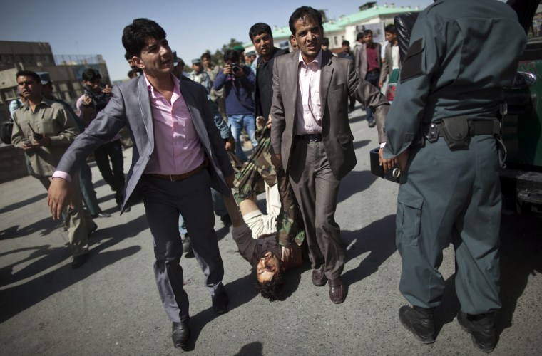 Image: Afghan security personnel in plain clothes carry the body of a would-be suicide bomber after he was killed during an attack at a Kabul police station