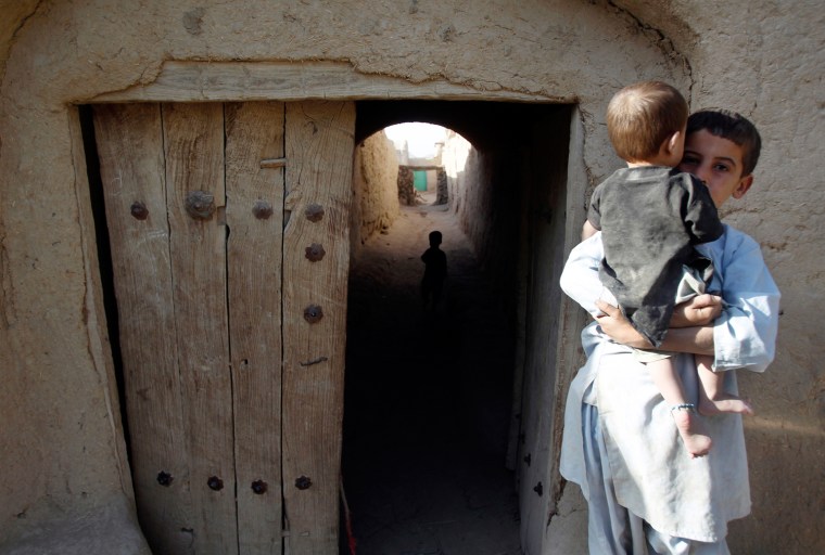 Image: An Afghan boy holds a baby in the village of Small Loi Kola